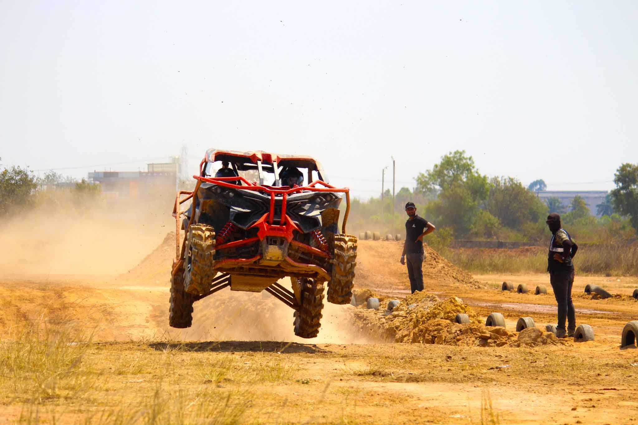 Orange and black off-road ATV jumping on dirt track with spectators watching during Ultimate Off Road ATV Driving Experience.